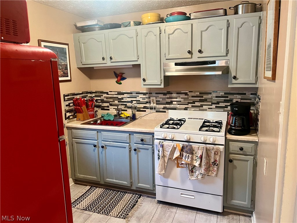 1714 Hillview Road Cleveland, OH 44112 - Photo 6 of 17 Kitchen featuring sink, gray cabinets, decorative backsplash, refrigerator, and white gas stove