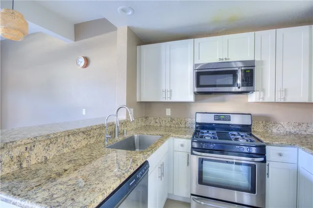 a kitchen with granite countertop a sink stove and microwave
