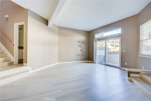 a view of an empty room with glass door and wooden floor