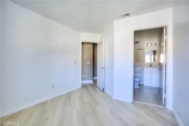 a view of a hallway with wooden floor and a bathroom