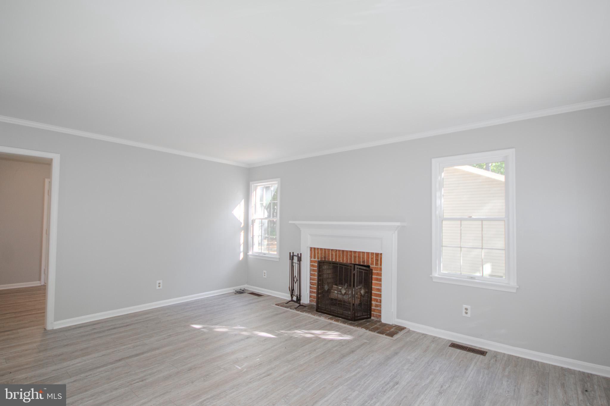 103 Ocean Parkway Ocean Pines, MD 21811 - Photo 7 of 44 an empty room with windows a fireplace and wooden floor