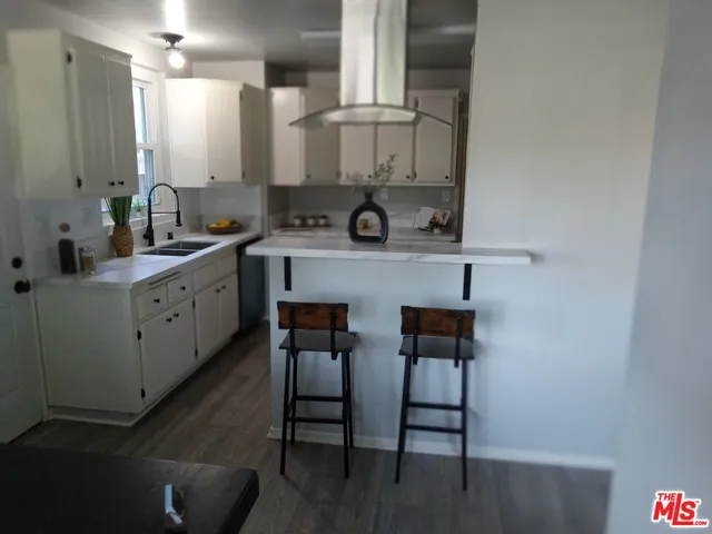 a kitchen with stainless steel appliances a table chairs in it and wooden floors