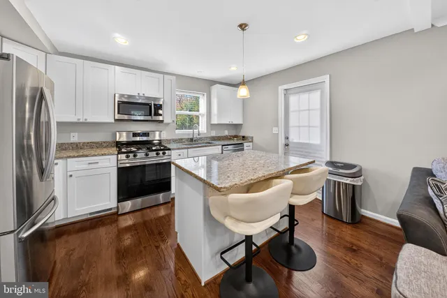 a kitchen with stainless steel appliances granite countertop a stove a sink a microwave a dining table and chairs