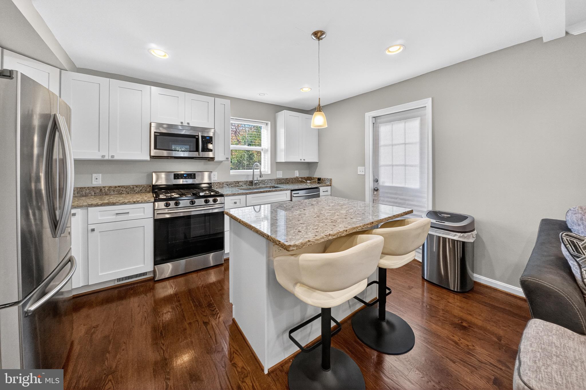 5211 Jay Street Northeast Washington, DC 20019 - Photo 6 of 17 a kitchen with stainless steel appliances granite countertop a stove a sink a microwave a dining table and chairs