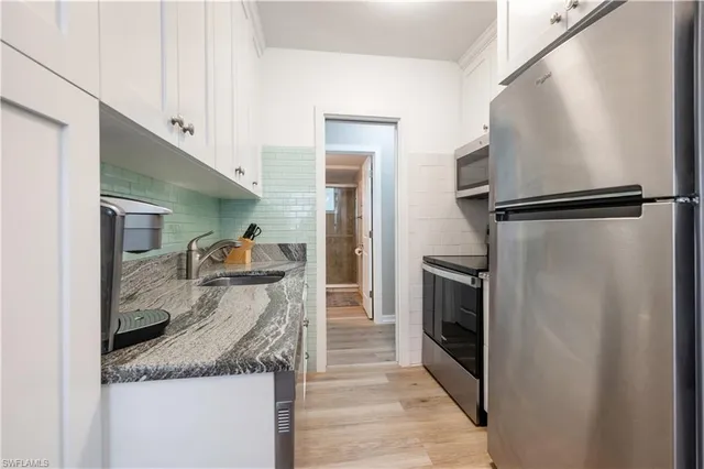 a kitchen with granite countertop a refrigerator and a sink