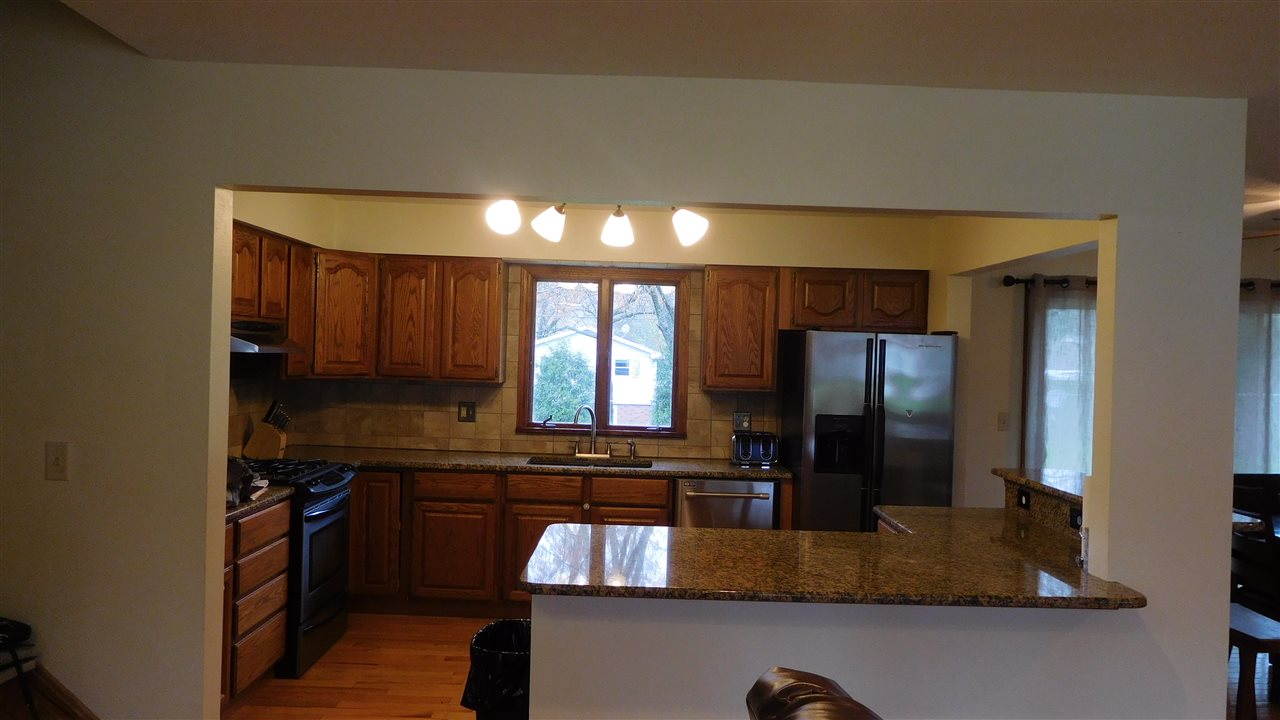4874 Braewild Road Rockford, IL 61107 - Photo 8 of 23 a kitchen with kitchen island granite countertop stainless steel appliances a sink stove and refrigerator