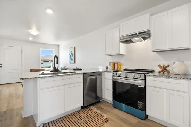 a kitchen with granite countertop a sink stainless steel appliances and cabinets