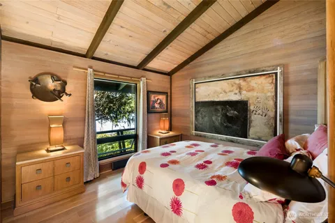 a bedroom with a bed dresser and wooden floor