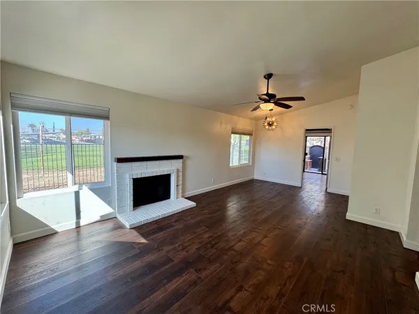 a view of an empty room with a fireplace and wooden floor