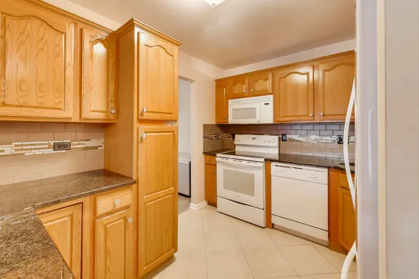 a kitchen with stainless steel appliances granite countertop a stove a sink and a refrigerator with cabinets
