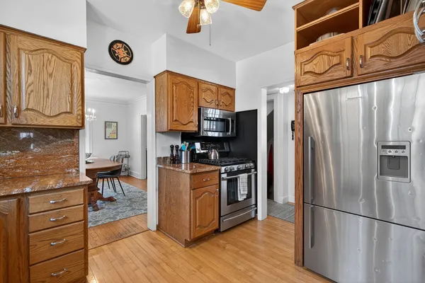 a kitchen with stainless steel appliances granite countertop a refrigerator stove and wooden floor