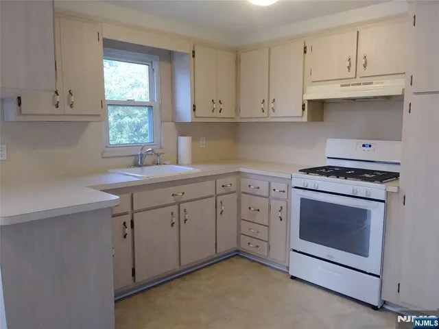 a kitchen with granite countertop white cabinets sink and window