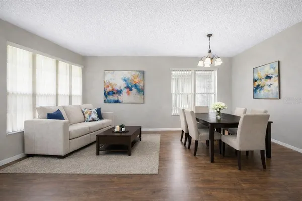 a living room with furniture two window and a wooden floor