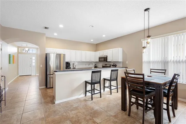 a kitchen with stainless steel appliances kitchen island granite countertop a table chairs and a refrigerator