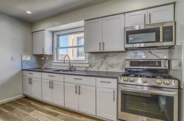 a kitchen with granite countertop a stove top oven microwave and cabinets