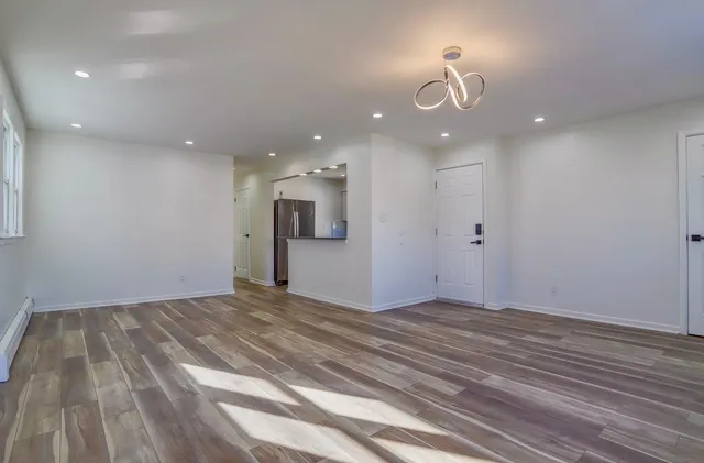 a view of an empty room with wooden floor and a ceiling fan