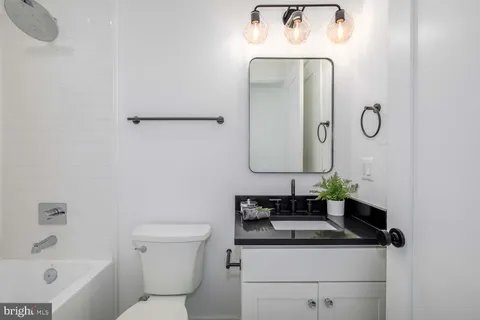 a bathroom with a granite countertop sink a toilet and a mirror
