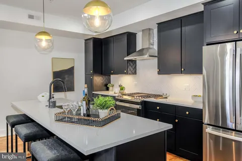 a kitchen with kitchen island granite countertop a sink cabinets and stainless steel appliances