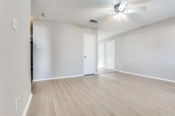an empty room with wooden floor fan and windows
