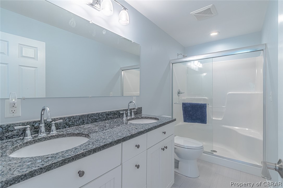 988 Queenstown Road Lancaster, VA 22503 - Photo 9 of 37 a bathroom with a granite countertop sink a toilet a mirror and shower