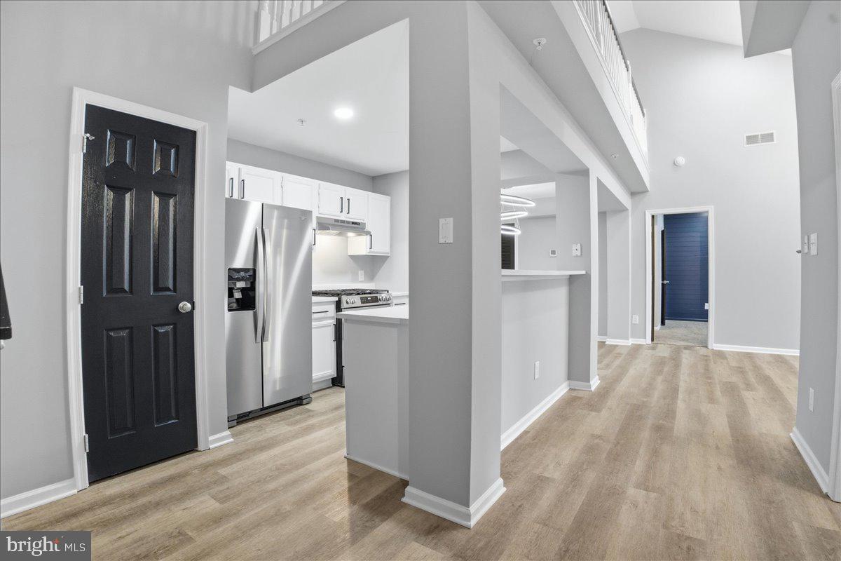 20419 Riverbend Square, Unit 301 Sterling, VA 20165 - Photo 9 of 25 a view of a hallway with wooden floor and a kitchen