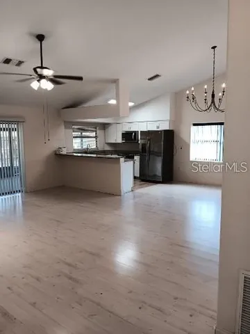 a large kitchen with stainless steel appliances a large counter top a chandelier and a wooden floor