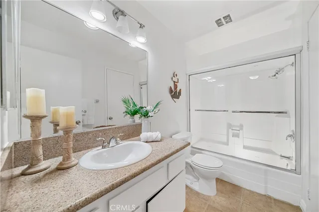 a bathroom with a granite countertop sink mirror and a toilet