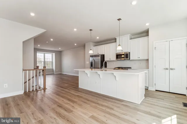 a large white kitchen with lots of counter space a sink appliances and cabinets