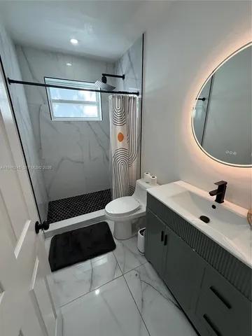 a white toilet sitting next to a bathroom sink and a shower