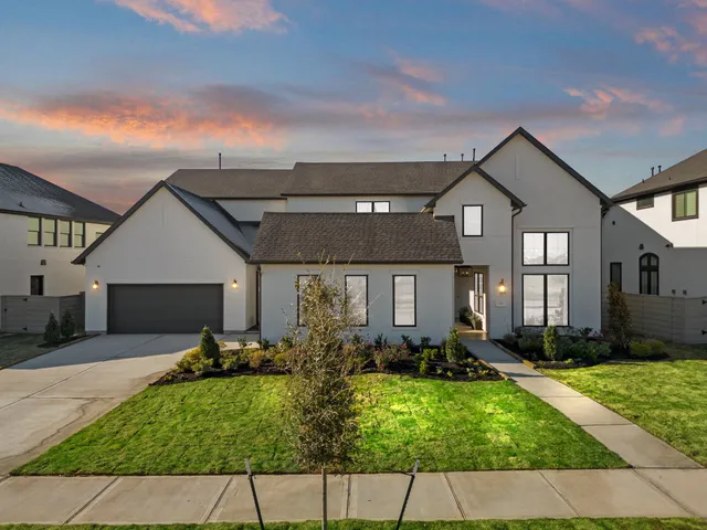 a view of a white house next to a yard with big trees