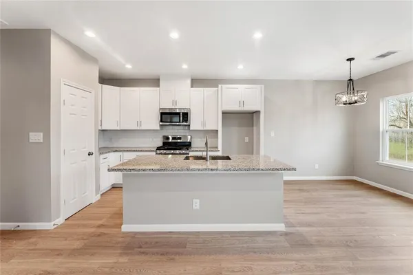 a kitchen with kitchen island a counter top space a sink cabinets and appliances