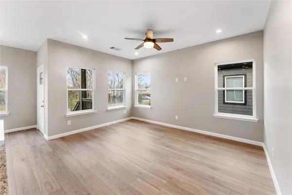 a view of an empty room with a window and wooden floor