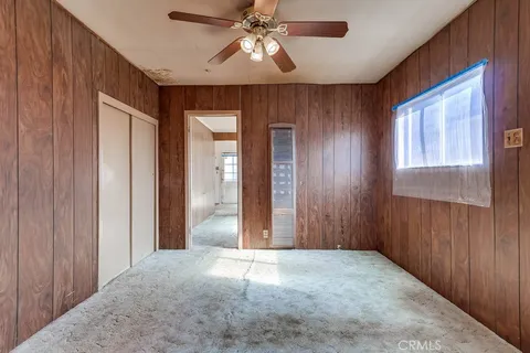 an empty room with chandelier fan and windows