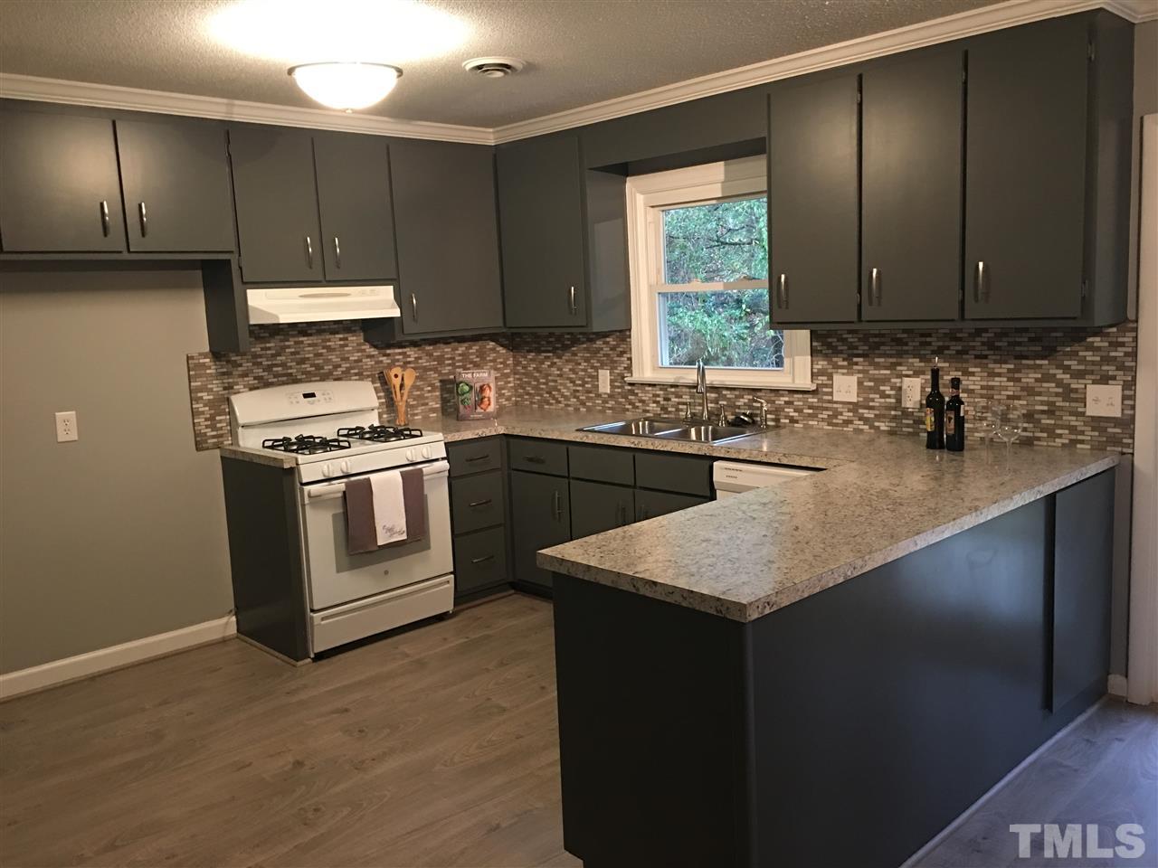 1303 Castlebay Road Durham, NC 27704 - Photo 3 of 21 a kitchen with stainless steel appliances granite countertop a sink stove and refrigerator