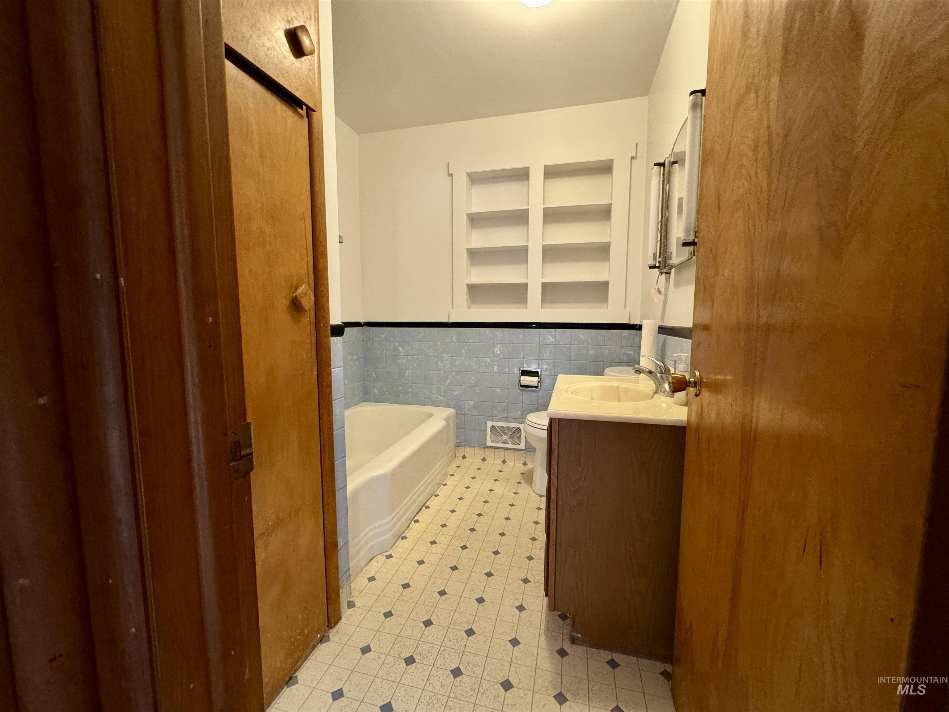 3989 North 2250 East Filer, ID 83328 - Photo 17 of 26 Full bathroom featuring vanity, tile walls, wainscoting, a bath, and light flooring