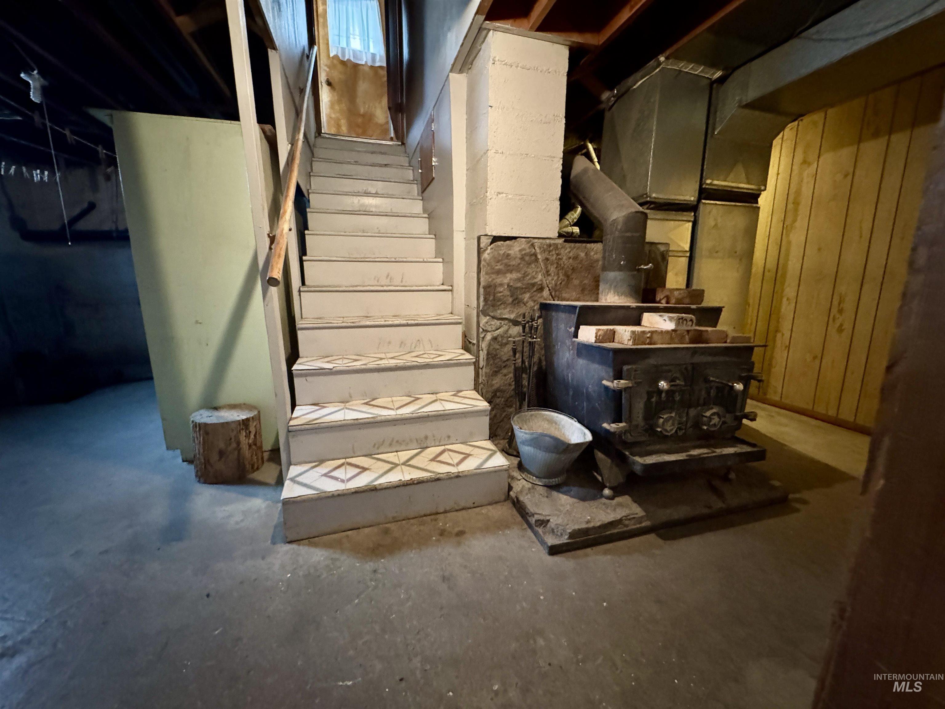 3989 North 2250 East Filer, ID 83328 - Photo 20 of 26 Stairs with concrete floors, a wood stove, and wood walls