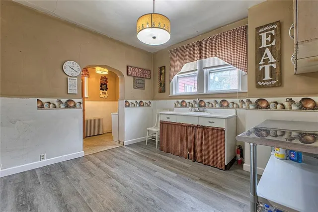 a kitchen with stainless steel appliances granite countertop a stove a sink dishwasher and a dining table with wooden floor