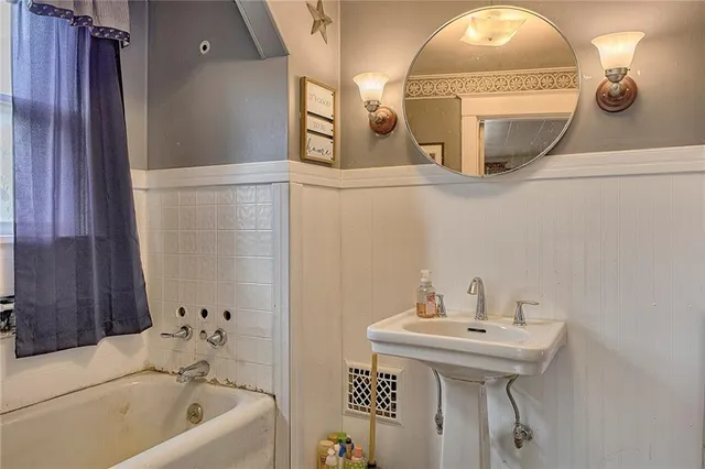 a bathroom with a sink and mirror with bathtub