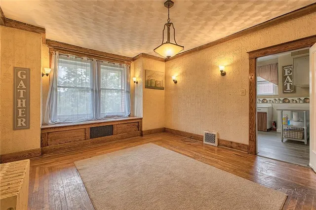 a view of an empty room with window and wooden floor