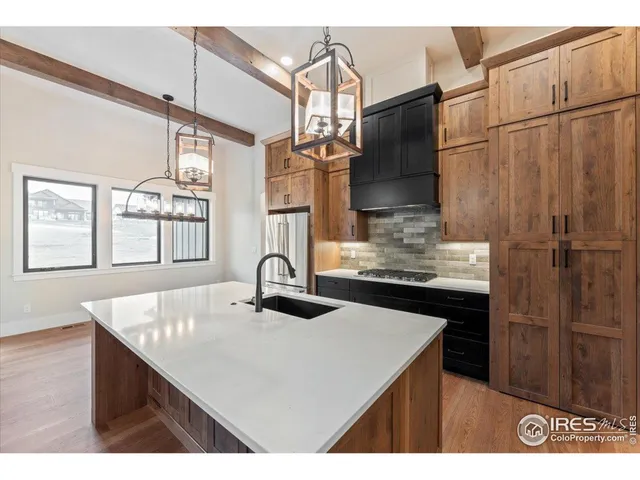 a kitchen with stainless steel appliances kitchen island granite countertop a refrigerator a stove and a sink with wooden floor