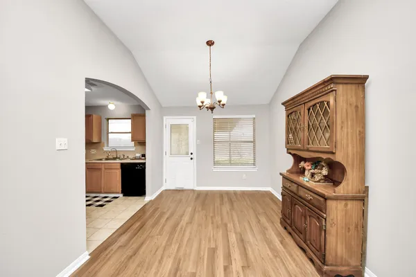 a kitchen with granite countertop a stove top oven a sink dishwasher a dining table and chairs with wooden floor