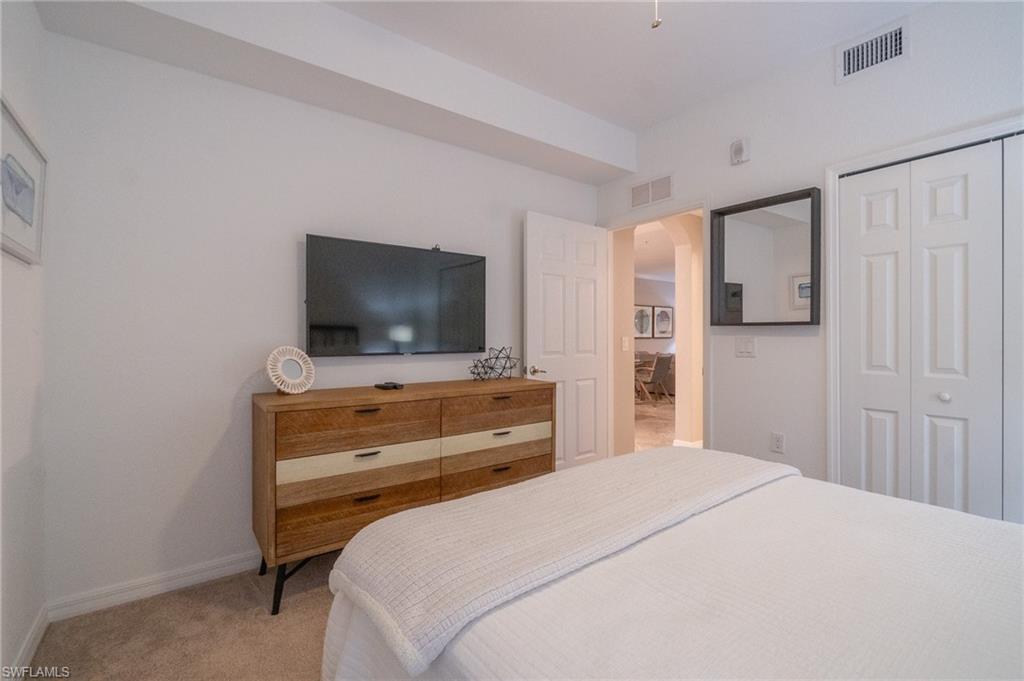 9596 Trevi Court, Unit 5414 Naples, FL 34113 - Photo 16 of 34 a bedroom with a bed and a flat screen tv