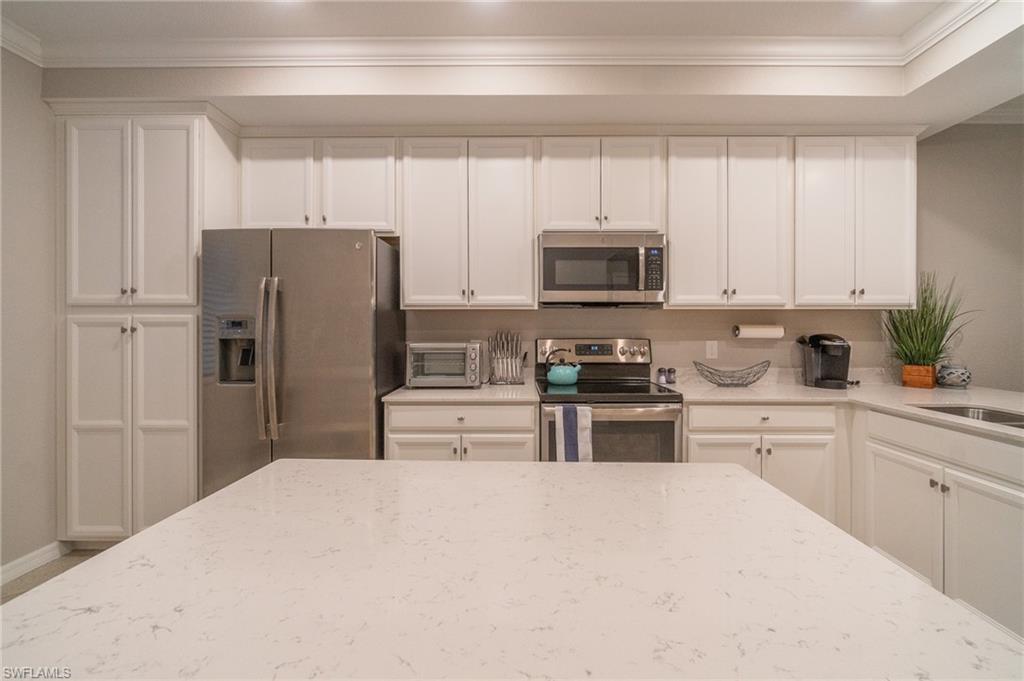 9596 Trevi Court, Unit 5414 Naples, FL 34113 - Photo 9 of 34 a kitchen with refrigerator a microwave a sink and cabinets