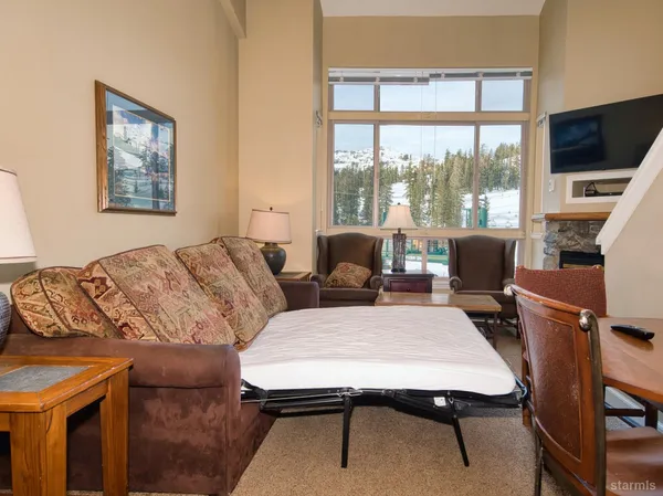 a living room with furniture a flat screen tv and a floor to ceiling window