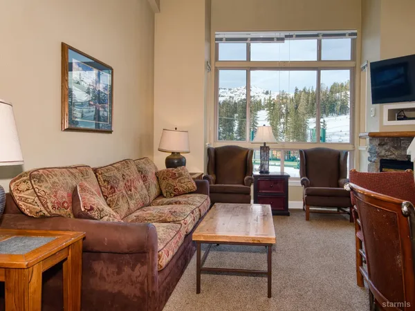 a living room with furniture a flat screen tv and a large window