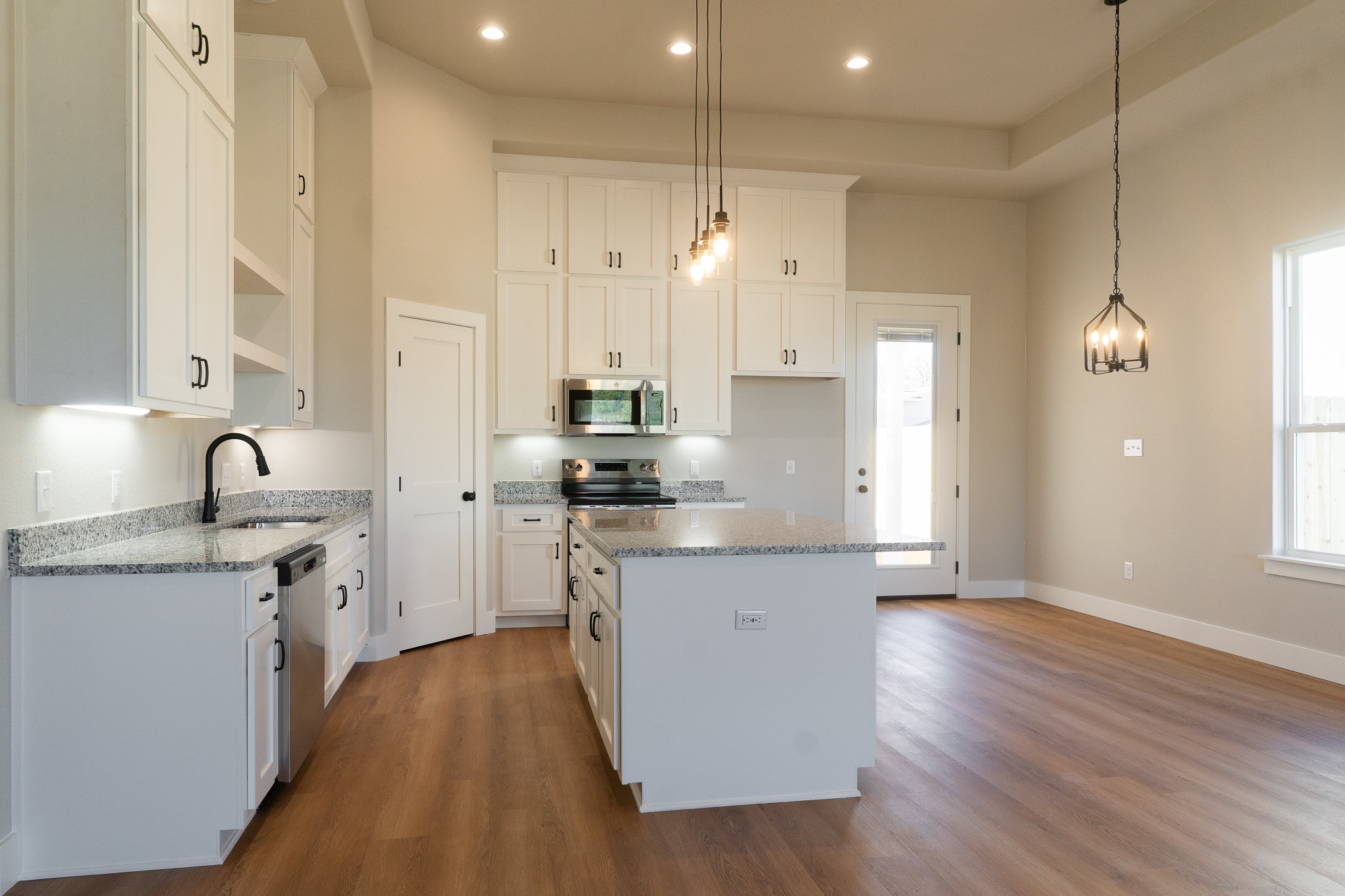 313 String Prairie Way Smithville, TX 78957 - Photo 7 of 18 a kitchen with stainless steel appliances a stove a sink a refrigerator and white cabinets with wooden floor