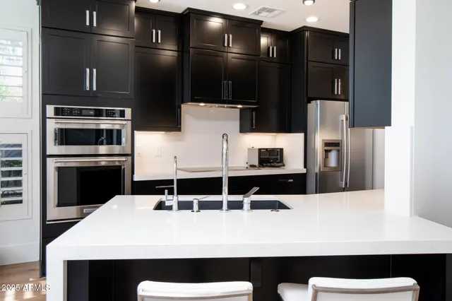 a living room with stainless steel appliances furniture wooden floor and a view of kitchen
