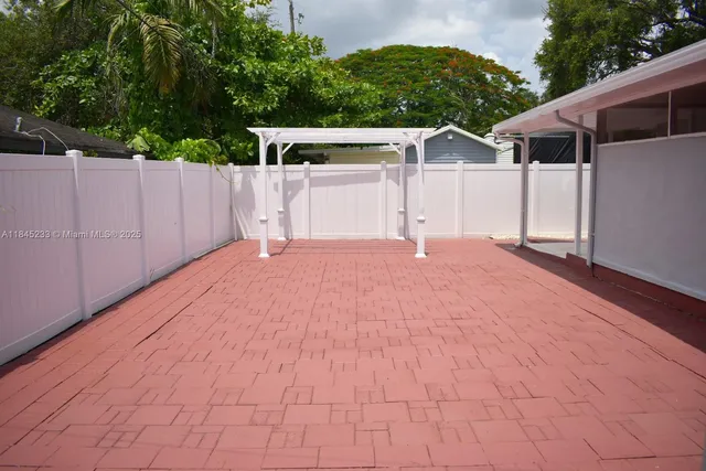 a backyard of a house with large trees and wooden fence