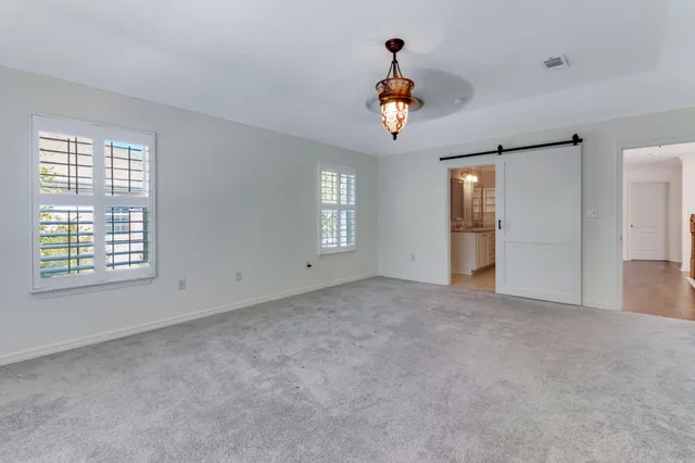 an empty room with windows and ceiling fan