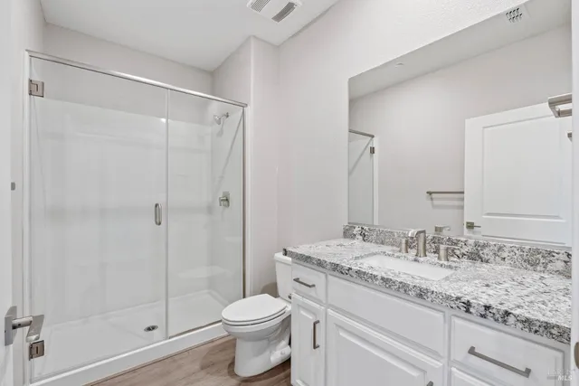a bathroom with a granite countertop sink a toilet and shower